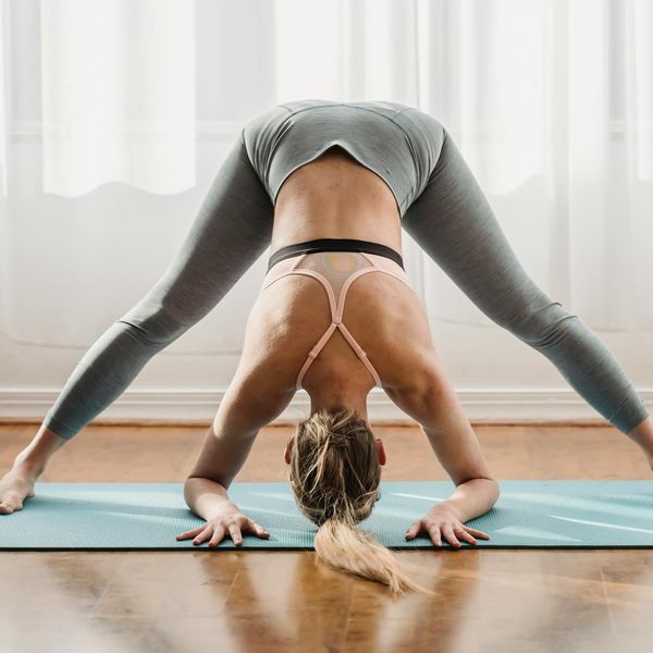 Woman in a calm yoga pose in a dark room with light blue accents.